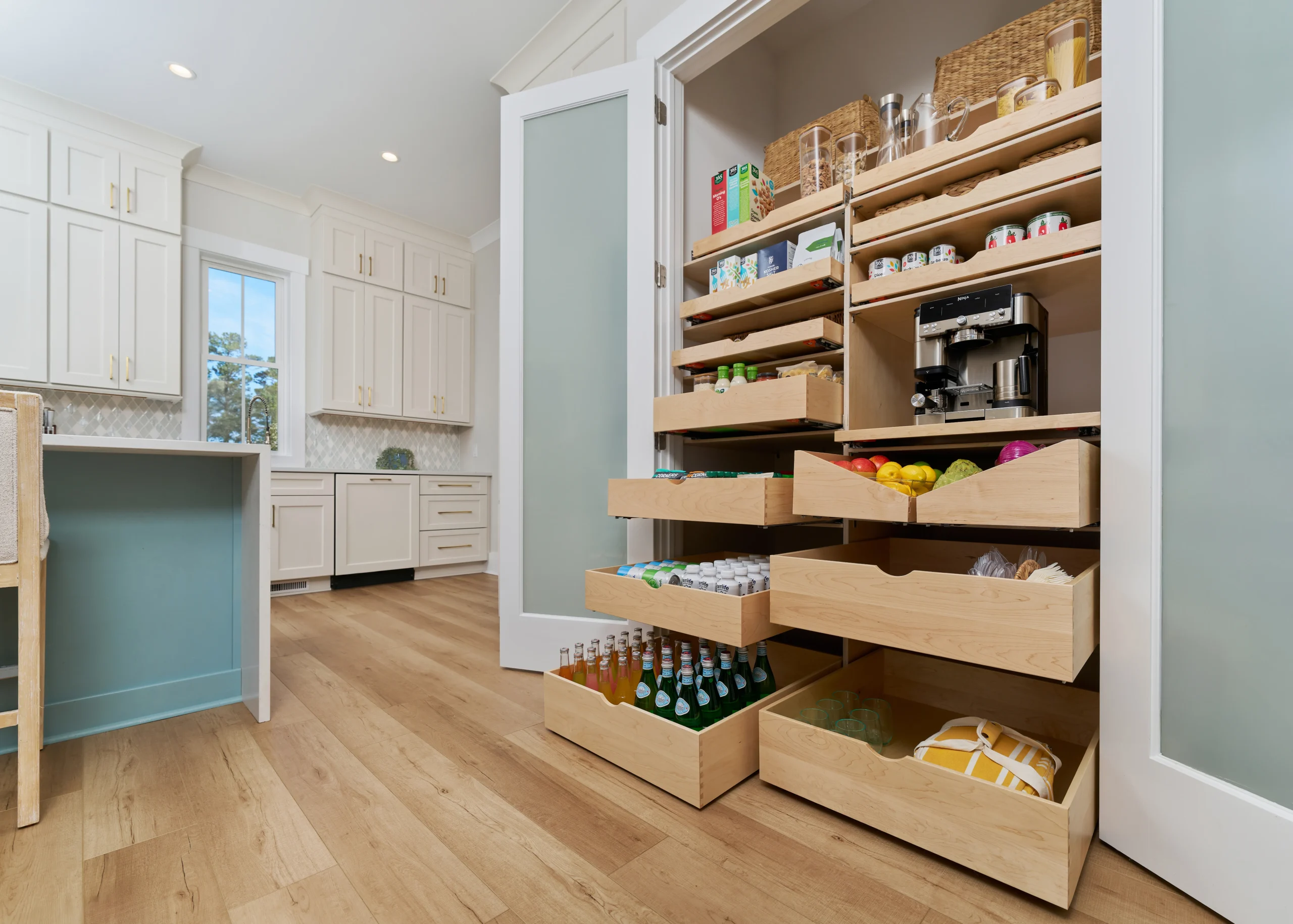 An open pantry with pull-out shelves and drawers filled with various food items and a coffee maker